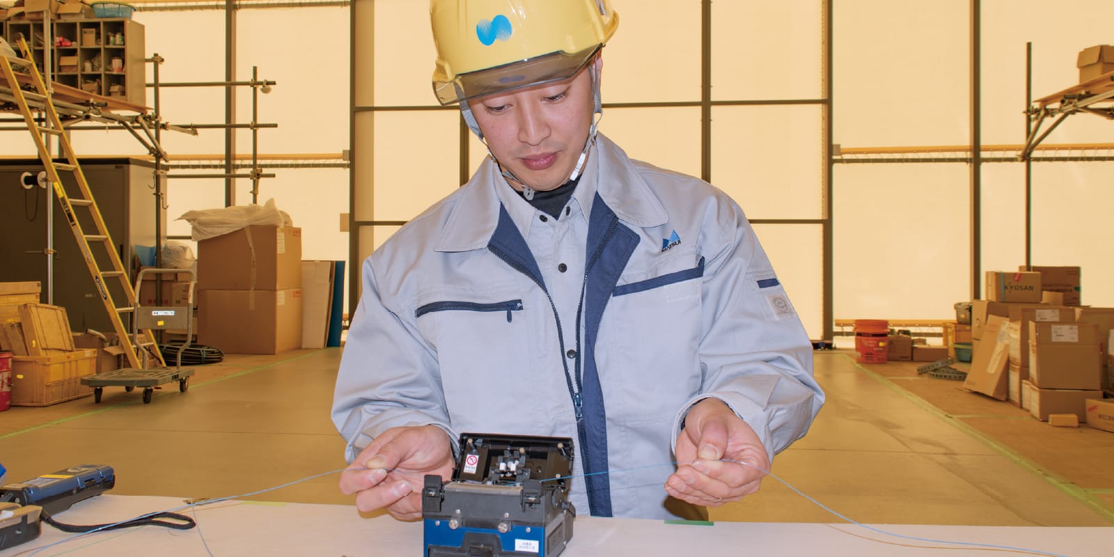 作業服とヘルメットを着用した男性が、光ファイバーの接続作業中